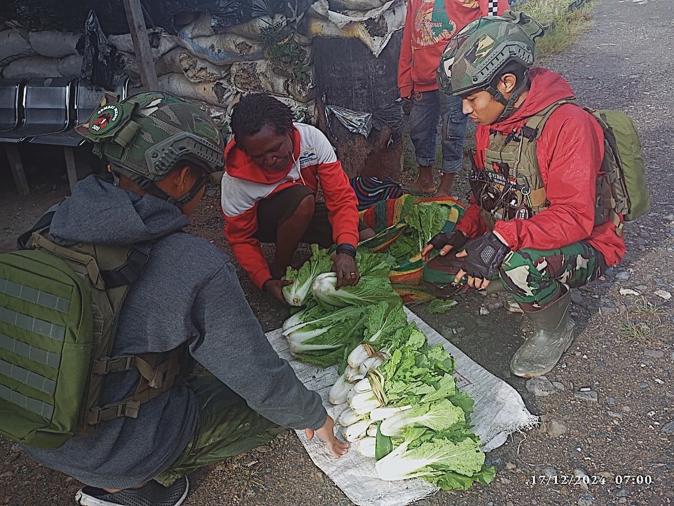 Satgas Yonif 509 Kostrad Laksanakan Program “Rosita” di Titik Kuat J2, Borong Hasil Tani Sebelum Sampai ke Pasar  Intan Jaya, Papua – Program “Rosita” (Borong Hasil Tani) yang rutin dilaksanakan oleh Satgas Yonif 509 Kostrad di Titik Kuat J2, yang dipimpin oleh Dan TK Lettu Inf Fardhana, terus mendapat sambutan hangat dari masyarakat. Dalam kegiatan ini, personel Satgas membeli hasil panen petani langsung di jalan sebelum mereka sampai ke pasar, memberikan kemudahan bagi para petani sekaligus mendorong perekonomian lokal. Sabtu (21/12/2024)  Sebagai bagian dari program rutin, para prajurit Satgas Yonif 509 Kostrad menunggu para petani di sekitar jalur menuju pasar. Hasil panen seperti umbi-umbian, sayuran, dan buah-buahan yang dibawa para petani langsung dibeli oleh personel Satgas dengan harga yang layak.  Lettu Inf Fardhana, Dan TK J2, menjelaskan bahwa program ini tidak hanya membantu petani dalam memasarkan hasil taninya, tetapi juga menjadi ajang komunikasi antara prajurit dan masyarakat setempat.  “Kami ingin mempermudah petani dengan membeli hasil panen mereka sebelum sampai ke pasar. Selain meringankan beban mereka, ini juga menjadi kesempatan bagi kami untuk berinteraksi langsung dengan masyarakat dan mendengar kebutuhan mereka,” ujar Lettu Inf Fardhana.  Para petani merasa sangat terbantu dengan adanya program ini. Salah satu petani, Mama Nelly, menyampaikan rasa terima kasihnya kepada TNI.  “Kami tidak perlu berjalan jauh ke pasar karena hasil panen kami sudah dibeli bapak-bapak TNI. Ini sangat membantu kami, dan kami juga merasa lebih dekat dengan TNI,” ujar Mama Nelly dengan penuh syukur.